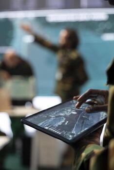 Army staff monitoring infantry unit on ongoing operation using his tablet, using surveillance radar system and a world map. IT professional working with reconnaissance gear. Close up. photo