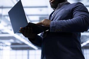 IT operative in data center implements backup solutions to protect against equipment data loss using laptop. Close up of IT expert resolving technical difficulties affecting mainframes using notebook photo