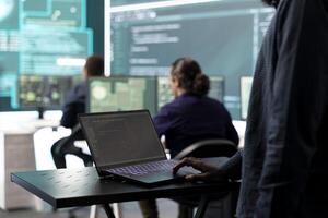 Governmental IT expert examines cyber threats on big screen and laptop, managing database hacking activity in high tech agency. Work on cyber defense to protect state secrets and networks. photo