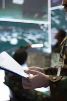 Soldier examining top secret operation details from the case file, going over important battlefield data to ensure defense mission success. Trooper operating in command post. Close up. photo