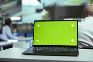 Laptop showing blank greenscreen display in a control center agency, people working with surveillance CCTV cameras to follow the delivery trucks around town. Global positioning system. photo