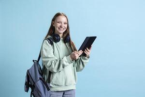 Overjoyed teenager using tablet, laughing at amusing social media posts on feed. Joyous person browsing internet websites, amused by funny memes, isolated over studio backdrop photo