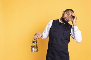 Restaurant butler working on serving clients with a headache, feeling tired and overworked in service oriented industry. Young caterer suffering from a painful migraine in studio. photo