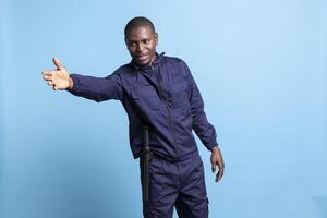 African american guy works as a security guard in front of the camera, restricting the access and pointing persons in another direction. Patrol officer is guiding people to left or right in studio. photo
