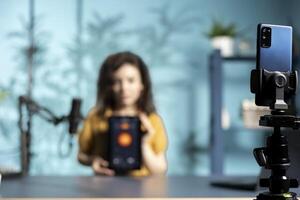 Focus on phone used by tech guru in studio to film smart light bulb tablet application presentation for online platforms. Close up of smartphone used by media star presenting IoT home automation photo