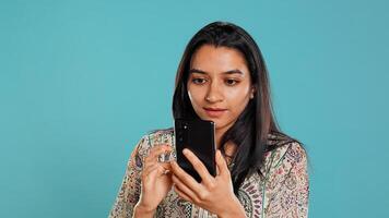 Woman scrolling on smartphone screen, doing online shopping, amazed by beautiful clothes. Portrait of relaxed person browsing internet websites, exclaiming in astonishment, studio background, camera B photo