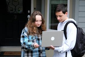 Happy young multiethnic couple spending time together at the park, studying while sitting at the table with laptop photo