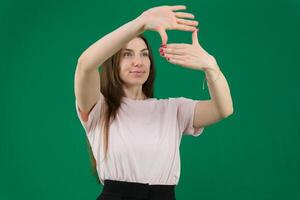 Smiling young woman hides face makes frame gesture takes photo keeps palm over eyes being in good mood wears casual white poloneck isolated over purple background captures moment pictures future
