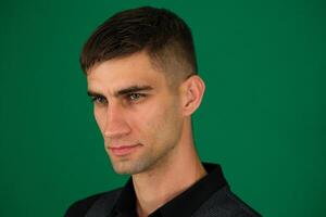 emotions of a handsome man guy on a green background chromakey close-up dark hair young man photo