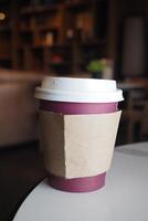 A Coffee Cup placed on a Table featuring a Smartphone in a Cozy Cafe Setting that feels inviting photo