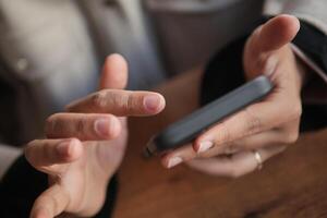 A detailed closeup view of hands utilizing a smartphone on a wooden table photo