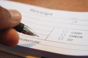 Signing the Receipt by Hand Using a Pen on the Payment Form Provided photo