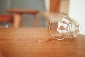 A glass has been accidentally spilled on a polished wooden table surface photo