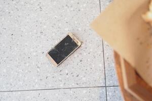 Top view of broken smart phone on tiles floor photo