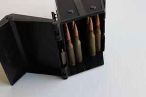 Standard 5.45 ammo in ammo storage box on white surface photo