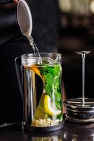 vitamin tonic tea with lemon, ginger and mint, on a dark background in a transparent teapot photo
