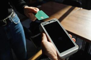 A man accepts payment from a customer through a credit card terminal in a store or cafe photo
