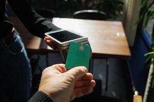 A man accepts payment from a customer through a credit card terminal in a store or cafe photo