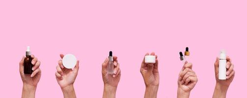 Female hands with different cosmetic products in container and bottles, pipettes on pink color background photo
