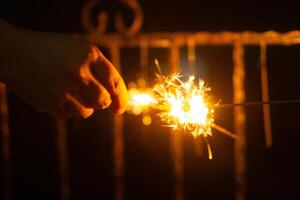 Playing firework sparkles in night with silhouette of hand of kids for new year event photo