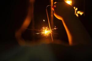 Playing firework sparkles in night with silhouette of hand of kids for new year event photo