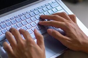 Close up image of hands typing on laptop computer keyboard and surfing the internet at home. Freelancer copywriter working project, typing text, edit something. Remote job concept photo