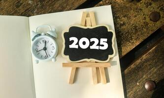 A small wooden-framed blackboard with 2025 on the notebook. Hello new year 2025 photo