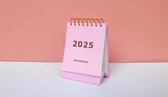 2025 calendar in pink isolated on pink background. Calendar and Note Pad Happy New year 2025. 2025 New Year resolutions goal, plan, and action concept photo