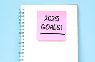 2025 Goals writing in notebook isolated on blue background. New year concept with typographic 2025. Motivational words to welcome the new year 2025 photo