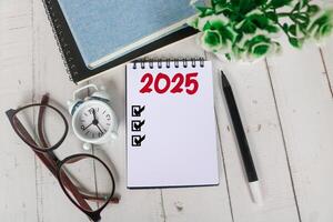 2025 New Year resolutions goals, plans, and resolutions concept. Planning checklist 2025 target on notebook with office desk background photo