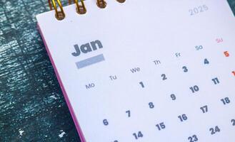 Close up of January 2025 in the pink 2025 calendar on the table. Calendar and Note Pad Happy New Year 2025. Zoomed in first of January 2025 in the calendar photo