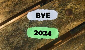 Inscription on the word goodbye 2024 on wooden table background. Bye 2024 on paper, hello 2025 photo
