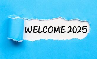 Welcome 2025 on white background and torn blue paper. New year concept with typographic welcome 2025 on paper photo