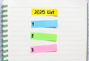 2025 List Notes on colorful paper in notebook. New year concept with typographic 2025. Motivational words to do list for the new year 2025 photo