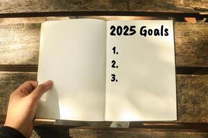 Writes 2025 Goals in a notebook. Blank book to fill in 2025 goals. Planning a 2025 to do list photo