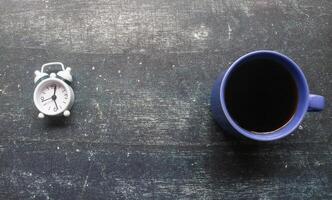 Blue cup of black coffee and alarm clock, top view on grey background with copy space photo