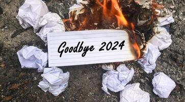 Paper is burning on fire and pile of paper waste with Goodbye 2024 written on it. new life and new year 2025 concept. 2024 paper is burning, say goodbye to 2024 photo