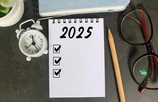 2025 New Year resolutions goals, plans, and resolutions concept. Planning checklist 2025 target on notebook with office desk background photo