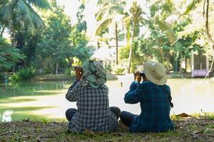 Two Asian boys use binoculars to study the local birds at school. Soft and selective focus. photo