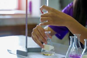 Close-up of a student performing an acid-base titration experiment. Concept of chemistry lab, science, experiment, skills, learning. photo