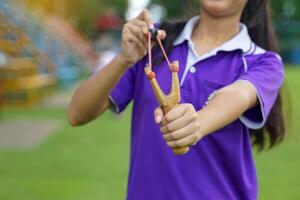 Hand holding Slingshot on green background It is a weapon made from a forked stick with rubber attached to a leather strip that holds bullets to be fired photo