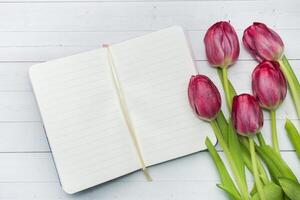 Concept greeting card Overhead view of a bouquet of tulips and notebook. copy space. photo
