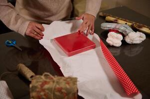 Wrapping a red box with festive gift paper on a holiday table photo