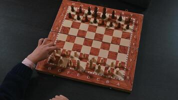 Child's hand playing chess on a wooden chessboard during a game session photo