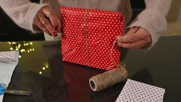 Woman Wrapping Christmas Gifts with Festive Red Polka Dot Paper and String photo