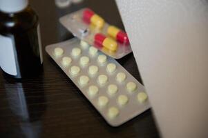Blisters of medications including capsules and tablets on a dark surface photo
