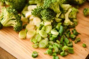Freshly chopped broccoli and green onions on a wooden cutting board photo