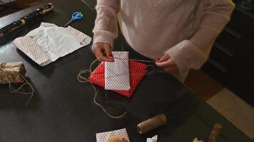 Woman Wrapping Christmas Gifts with Red and White Wrapping Paper and String on a Table photo