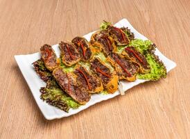 Crispy Beef Brisket with carrot and lettuce leaves served in tray dish isolated on wooden table side view of hong kong food photo