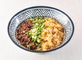 Sichuan Dan Dan Noodles or Wan Zamian topped with sauce, minced pork, Sichuan peppercorns, and peanuts served in bowl isolated on white background side view of hong kong food photo
